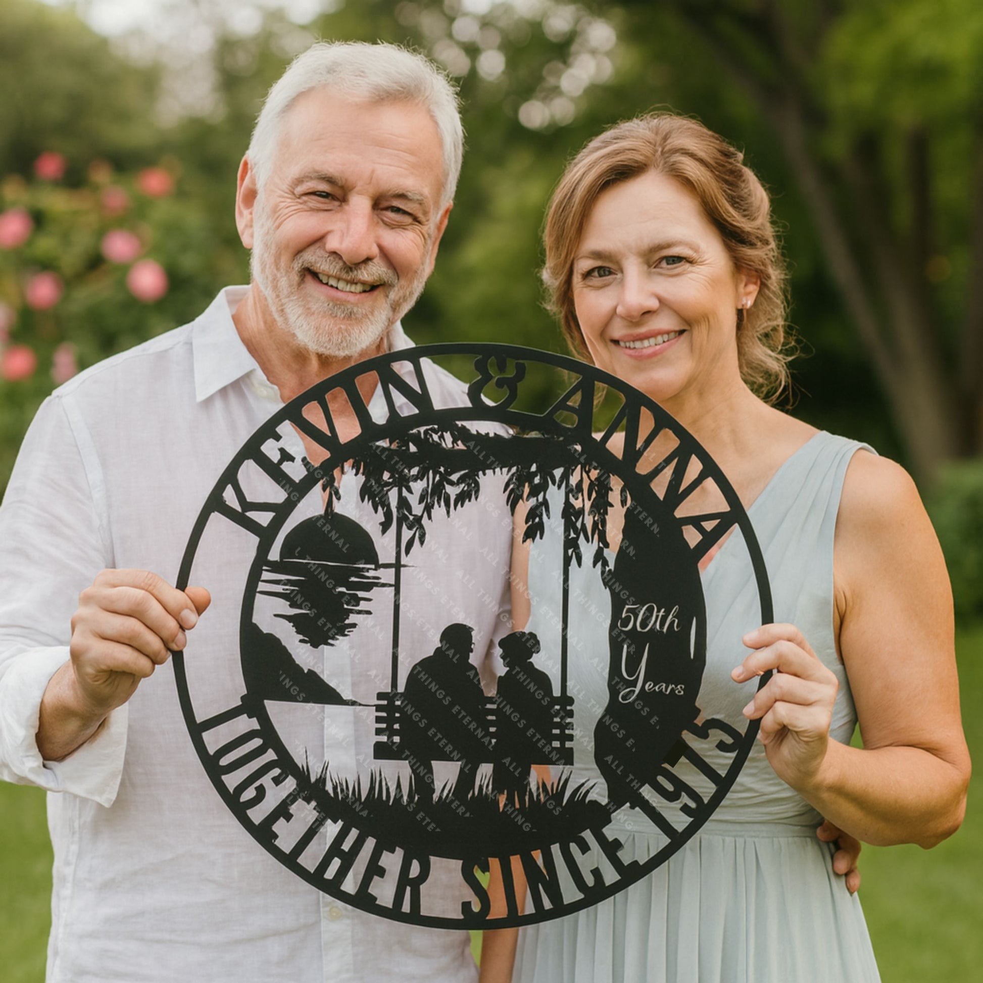 Couple holding a decorative sign celebrating their 50th anniversary outdoors.